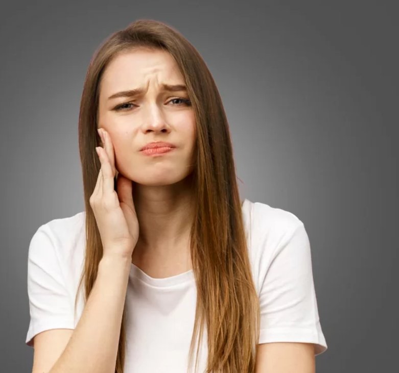Paciente com dor de dente segurando o rosto, precisando de atendimento odontológico de urgência